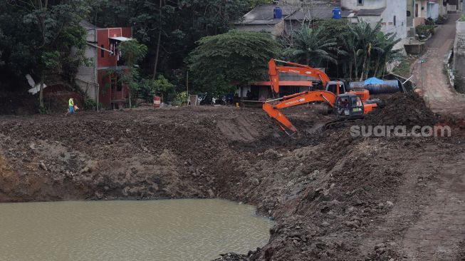 Pekerja menggunakan alat berat mengeruk lahan yang akan dijadikan Waduk Brigif, Jagakarsa, Jakarta, Minggu (27/3/2022). [Suara.com/Angga Budhiyanto]