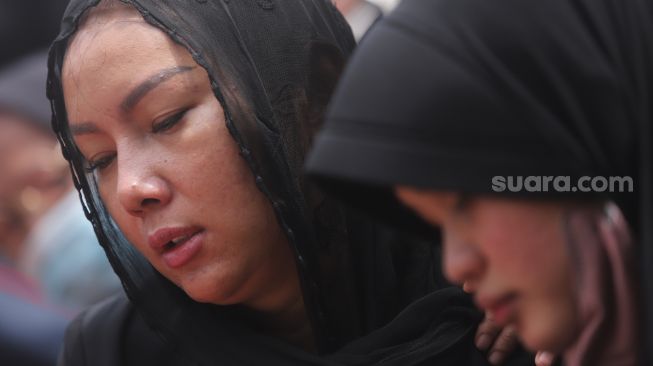 Kalina Oktarani bersama keluarga berdoa di samping makam sang ibunda Erlan Wardhania di TPU Taman Abadi, Ciputat, Tangerang Selatan, Banten, Senin (28/3/2022). [Suara.com/Angga Budhiyanto]