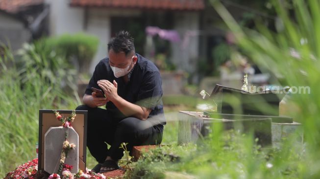 Presenter Vicky Prasetyo berdoa di samping makam ibunda Kalina Oktarani, Erlan Wardhania di TPU Taman Abadi, Ciputat, Tangerang Selatan, Banten, Senin (28/3/2022). [Suara.com/Angga Budhiyanto]