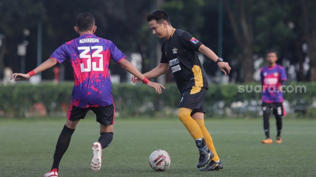 Pemain Selebritis FC Delon Thamrin membawa bola saat mengikuti sesi latihan di Lapangan ABC, Kompleks Gelora Bung Karno, Jakarta, Senin (28/3/2022). [Suara.com/Angga Budhiyanto]