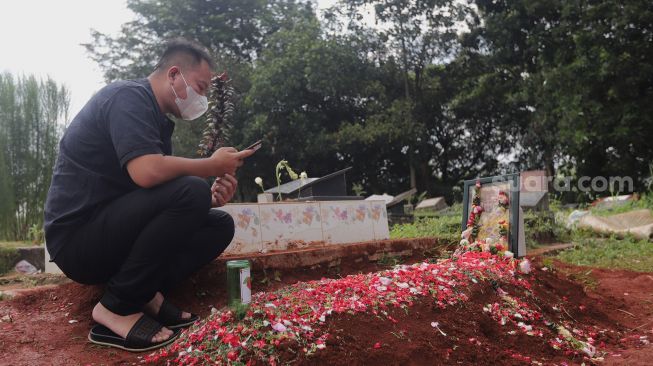 Presenter Vicky Prasetyo berdoa di samping makam ibunda Kalina Oktarani, Erlan Wardhania di TPU Taman Abadi, Ciputat, Tangerang Selatan, Banten, Senin (28/3/2022). [Suara.com/Angga Budhiyanto]