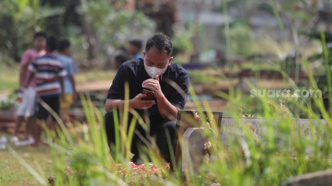 Presenter Vicky Prasetyo berdoa di samping makam ibunda Kalina Oktarani, Erlan Wardhania di TPU Taman Abadi, Ciputat, Tangerang Selatan, Banten, Senin (28/3/2022). [Suara.com/Angga Budhiyanto]