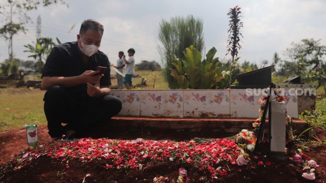 Presenter Vicky Prasetyo berdoa di samping makam ibunda Kalina Oktarani, Erlan Wardhania di TPU Taman Abadi, Ciputat, Tangerang Selatan, Banten, Senin (28/3/2022). [Suara.com/Angga Budhiyanto]