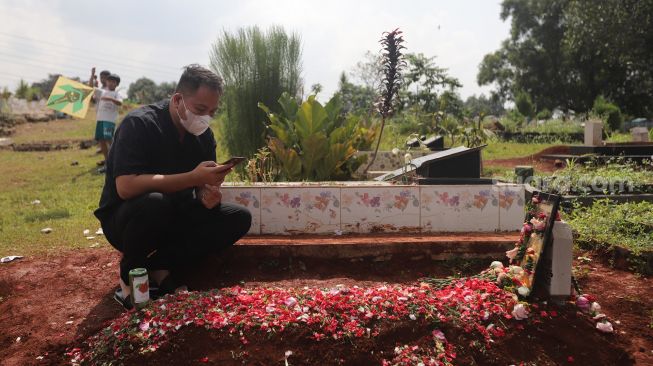 Presenter Vicky Prasetyo berdoa di samping makam ibunda Kalina Oktarani, Erlan Wardhania di TPU Taman Abadi, Ciputat, Tangerang Selatan, Banten, Senin (28/3/2022). [Suara.com/Angga Budhiyanto]