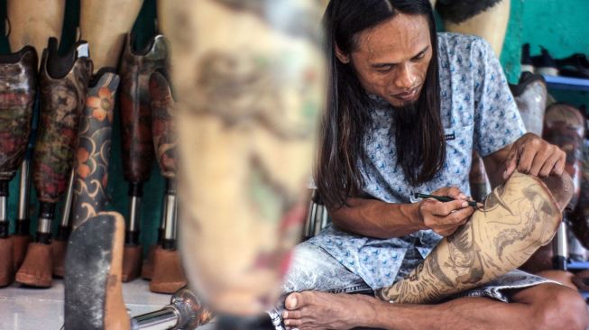 Perajin yang juga penyandang disabilitas Ronald Regen (33), memasangkan kaki palsu yang telah selesai dibuat kepada pelanggannya di Cileungsi, Kabupaten Bogor, Jawa Barat, Senin (28/3/2022).  ANTARA FOTO/Yulius Satria Wijaya