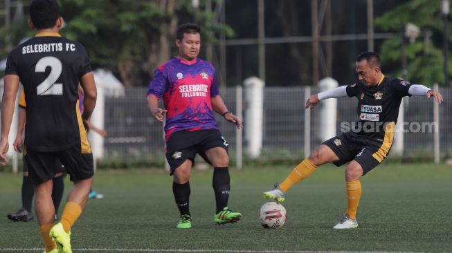 Pemain Selebritis FC Rico Ceper berusaha melewati lawan saat mengikuti sesi latihan di Lapangan ABC, Kompleks Gelora Bung Karno, Jakarta, Senin (28/3/2022). [Suara.com/Angga Budhiyanto]