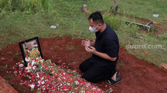 Presenter Vicky Prasetyo berdoa di samping makam ibunda Kalina Oktarani, Erlan Wardhania di TPU Taman Abadi, Ciputat, Tangerang Selatan, Banten, Senin (28/3/2022). [Suara.com/Angga Budhiyanto]