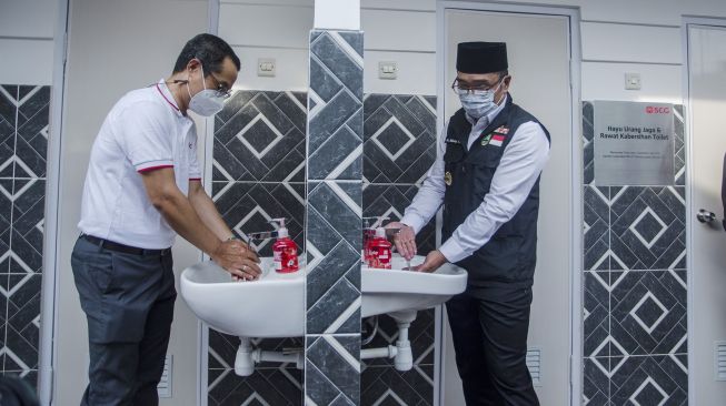 Gubernur Jawa Barat Ridwan Kamil (kanan) bersama Presiden Direktur PT. SCG Indonesia Chakkapong Yingwattanathaworn (kiri) mencuci tangan di toilet komunal daur ulang di Kelurahan Pasirluyu, Bandung, Jawa Barat, Selasa (29/3/2022).  ANTARA FOTO/Novrian Arbi