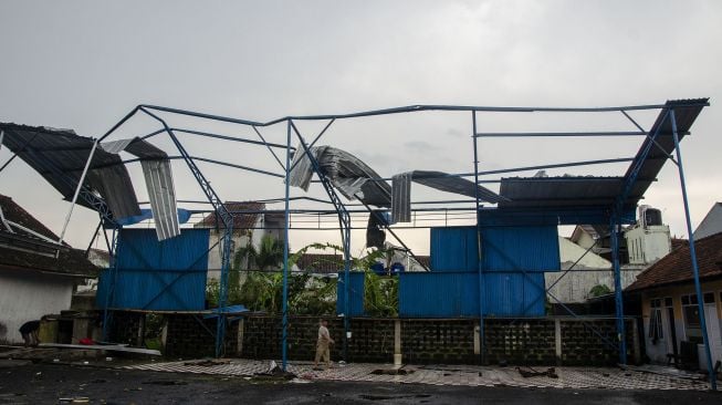 Warga membereskan atap baja ringan yang roboh setelah diterjang angin puting beliung di Desa Dewasari, Kabupaten Ciamis, Jawa Barat, Selasa (29/3/2022).  ANTARA FOTO/Adeng Bustomi