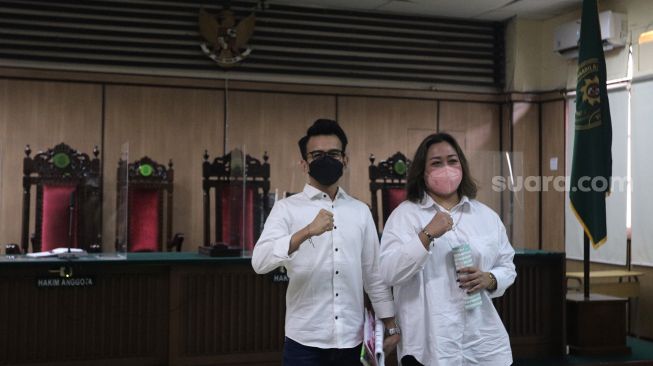 Terdakwa Adam Deni (kiri) dan Ni Made Dwita Anggari bersiap mengikuti sidang dengan agenda pembacaan putusan sela kasus pelanggaran Undang-Undang ITE di Pengadilan Negeri Jakarta Utara, Jakarta, Selasa (29/3/2022). [Suara.com/Angga Budhiyanto]