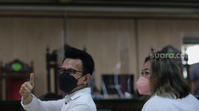 Terdakwa Adam Deni (kiri) dan Ni Made Dwita Anggari bersiap mengikuti sidang dengan agenda pembacaan putusan sela kasus pelanggaran Undang-Undang ITE di Pengadilan Negeri Jakarta Utara, Jakarta, Selasa (29/3/2022). [Suara.com/Angga Budhiyanto]