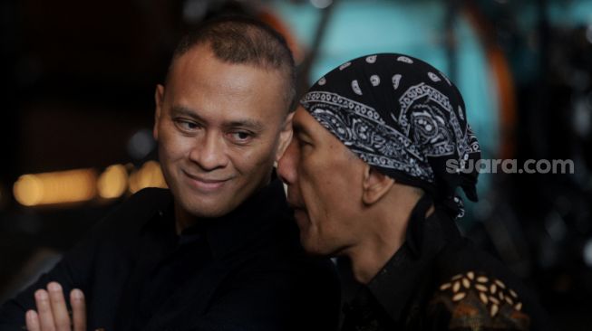 Giitaris grup musik Dewa 19 Andra Junaidi Ramadhan (kiri) berbincang dengan pemain bass Yuke Sampurna saat acara perilisan lagu "Juliette" di Holywings Kemang, Jakarta, Rabu (30/3/2022). [Suara.com/Angga Budhiyanto]