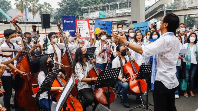 Komposer Addie MS menjadi konduktor orkestra saat menggelar seruan aksi damai di Depan Kedutaan Besar Rusia di Kuningan, Jakarta Selatan, Rabu (30/2/2022). [Suara.com/Alfian Winanto]