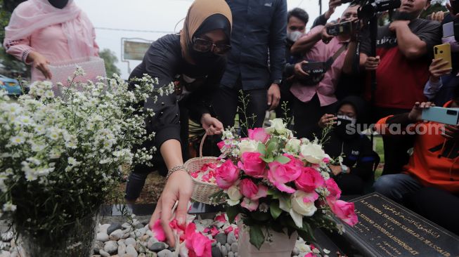 Mantan Politikus Angelina Sondakh menaburkan bunga saat berziarah ke makam suaminya, Adjie Massaid di TPU Jeruk Purut, Jakarta, Rabu (30/3/2022). [Suara.com/Angga Budhiyanto]