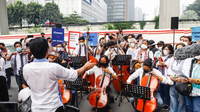 Komposer Addie MS menjadi konduktor orkestra saat menggelar seruan aksi damai di Depan Kedutaan Besar Rusia di Kuningan, Jakarta Selatan, Rabu (30/2/2022). [Suara.com/Alfian Winanto]