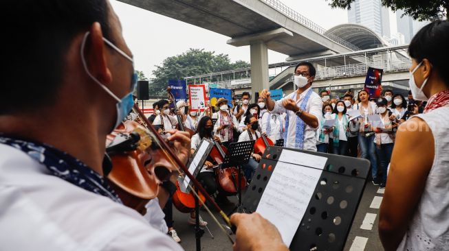 Komposer Addie MS menjadi konduktor orkestra saat menggelar seruan aksi damai di Depan Kedutaan Besar Rusia di Kuningan, Jakarta Selatan, Rabu (30/2/2022). [Suara.com/Alfian Winanto]