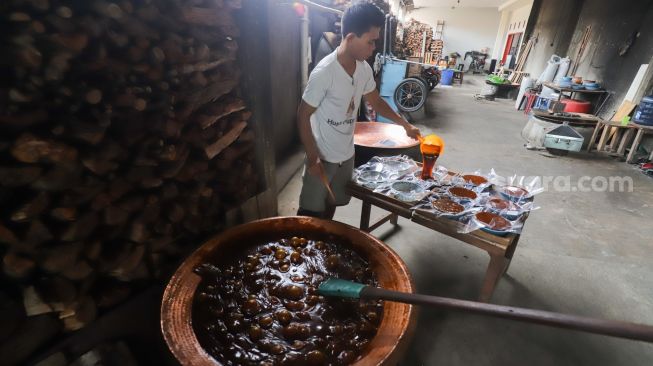 Pekerja menuang dodol betawi ke dalam wadah di rumah produksi Dodol Betawi Sari Rasa Ibu Yuyun, Jakarta Selatan, Kamis (31/3/2022). [Suara.com/Alfian Winanto]