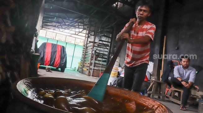 Pekerja mengaduk dodol betawi di dalam kuali di rumah produksi Dodol Betawi Sari Rasa Ibu Yuyun, Jakarta Selatan, Kamis (31/3/2022). [Suara.com/Alfian Winanto]