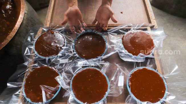 Pekerja menunjukan dodol betawi yang sudah ditaruh dalam wadah di rumah produksi Dodol Betawi Sari Rasa Ibu Yuyun, Jakarta Selatan, Kamis (31/3/2022). [Suara.com/Alfian Winanto]