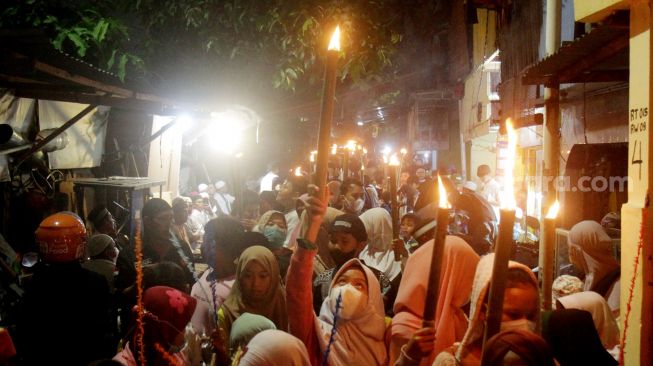 Sejumlah warga dan anak-anak mengikuti pawai obor di Jalan Menteng Jaya, Jakarta Pusat, Kamis (31/3/2022).  [Suara.com/Oke Atmaja]
