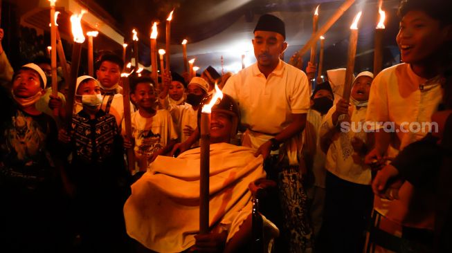 Sejumlah warga dan anak-anak mengikuti pawai obor di Menteng, Jakarta Pusat, Kamis (31/3/2022). [Suara.com/Alfian Winanto]