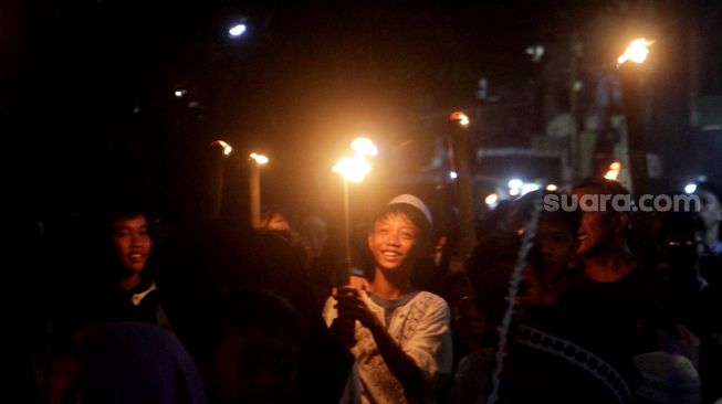 Sejumlah warga dan anak-anak mengikuti pawai obor di Jalan Menteng Jaya, Jakarta Pusat, Kamis (31/3/2022).  [Suara.com/Oke Atmaja]
