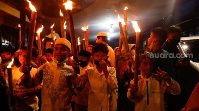 Sejumlah warga dan anak-anak mengikuti pawai obor di Menteng, Jakarta Pusat, Kamis (31/3/2022). [Suara.com/Alfian Winanto]