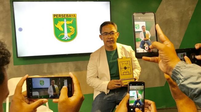 Pelatih Persebaya Aji Santoso membawa piala pelatih terbaik Liga 1 musim kompetisi 2021/2022 di Surabaya, Jumat (1/4/2022). ANTARA/Fiqih Arfani.