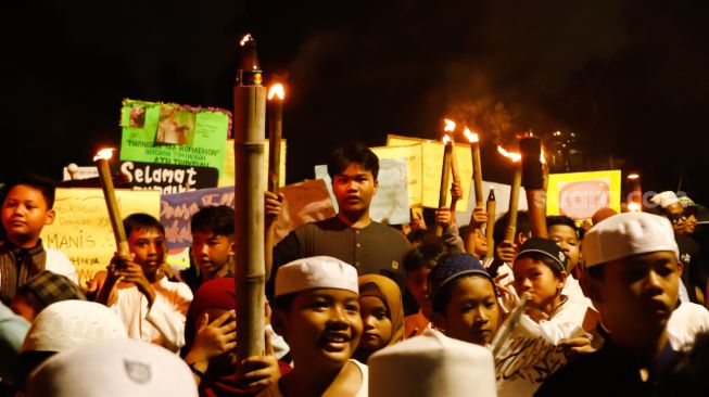 Sejumlah warga dan anak-anak mengikuti pawai obor di Menteng, Jakarta Pusat, Kamis (31/3/2022). [Suara.com/Alfian Winanto]