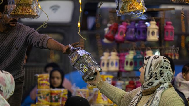 Seorang wanita melihat lentera Ramadhan tradisional di sebuah pasar di distrik Sayyida Zeinab, Kairo, Mesir, Rabu (30/3/2022). [Khaled DESOUKI / AFP]