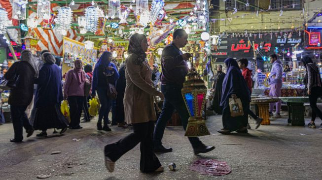 Seorang pria Mesir membawa lentera Ramadhan yang dibelinya di sebuah pasar di distrik Sayyida Zeinab, Kairo, Mesir, Rabu (30/3/2022). [Khaled DESOUKI / AFP]