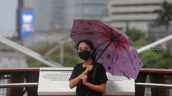 Warga menikmati suasana di Jembatan Penyeberangan Orang (JPO) Pinisi Karet-Sudirman, Jakarta, Minggu (3/4/2022). [Suara.com/Angga Budhiyanto]