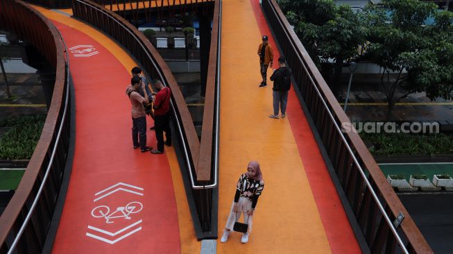 Warga berfoto di Jembatan Penyeberangan Orang (JPO) Pinisi Karet-Sudirman, Jakarta, Minggu (3/4/2022). [Suara.com/Angga Budhiyanto]