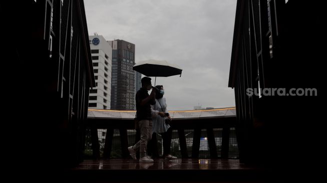 Warga berjalan di Jembatan Penyeberangan Orang (JPO) Pinisi Karet-Sudirman, Jakarta, Minggu (3/4/2022). [Suara.com/Angga Budhiyanto]