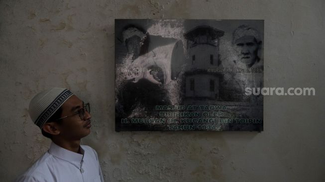 Pengurus Masjid Jami Maulana Hasanuddin, Fachrie Aie (30) menunjukkan foto pendiri masjid yang terpasang di salah satu sudut dinding di Cikoko, Pancoran, Jakarta, Minggu (3/4/2022). [Suara.com/Angga Budhiyanto]