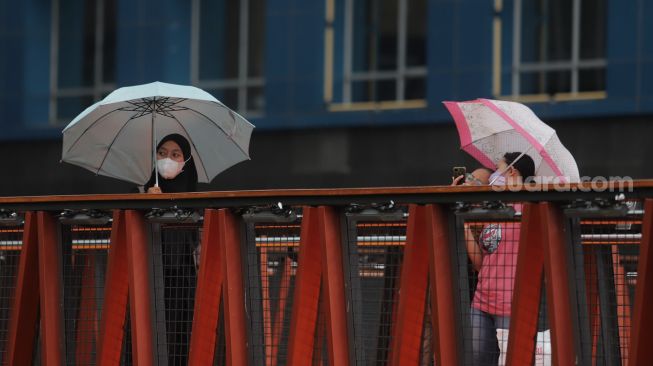 Warga berfoto di Jembatan Penyeberangan Orang (JPO) Pinisi Karet-Sudirman, Jakarta, Minggu (3/4/2022). [Suara.com/Angga Budhiyanto]