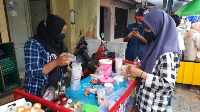 Heni Yuli Astuti, pedagang es buah melayani pembeli di Kampung Ramadhan Jogokariyan, Mantrijeron, Kota Jogja, Senin (4/4/2022). [Muhammad Ilham Baktora / SuaraJogja.id]