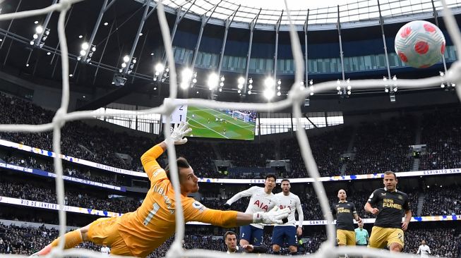 Striker Tottenham Hotspur Son Heung-Min (tengah) menyaksikan tembakannya mengalahkan kiper Newcastle United Martin Dubravka (kiri) untuk gol ketiga mereka saat pertandingan sepak bola Liga Premier Inggris antara Tottenham Hotspur dan Newcastle United di Stadion Tottenham Hotspur, London, Inggris, Minggu (3/4/2022). [Glyn KIRK / AFP]
