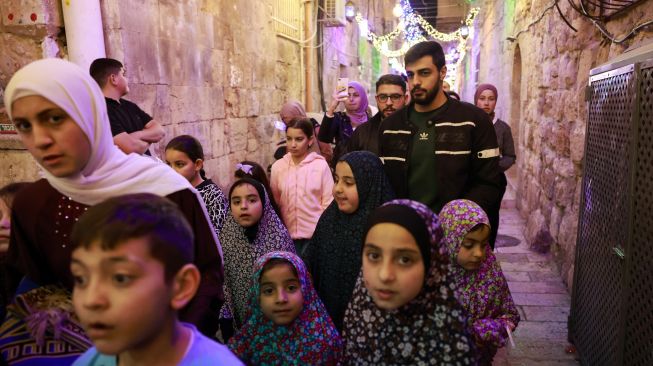 Warga Palestina berjalan menyusuri jalan di Kota Tua Yerusalem, Sabtu (2/4/2022). [Menahem KAHANA / AFP]
