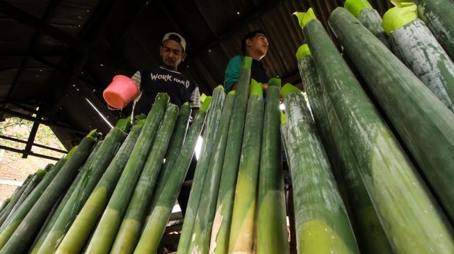 Pekerja mengisi santan ke dalam leumang bambu sebelum dibakar di Desa Blang Rayeuk, Lhokseumawe, Aceh, Minggu (3/4/2022). [ANTARA FOTO/Rahmad/YU]
