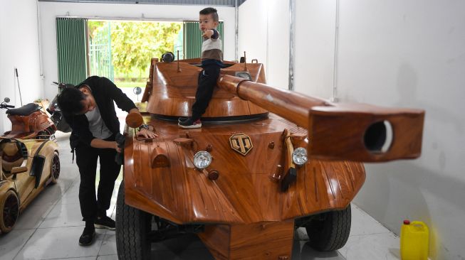 Truong Van Dao membersihkan tank kayu yang dibuatnya dari minibus tua di sebuah daerah perumahan di provinsi Bac Ninh, Vietnam, Senin (28/3/2022). [Nhac NGUYEN / AFP]
