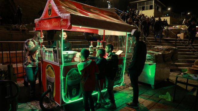 Warga Palestina membeli makanan ringan di luar gerbang Damaskus di Kota Tua Yerusalem, Sabtu (2/4/2022). [Menahem KAHANA / AFP]
