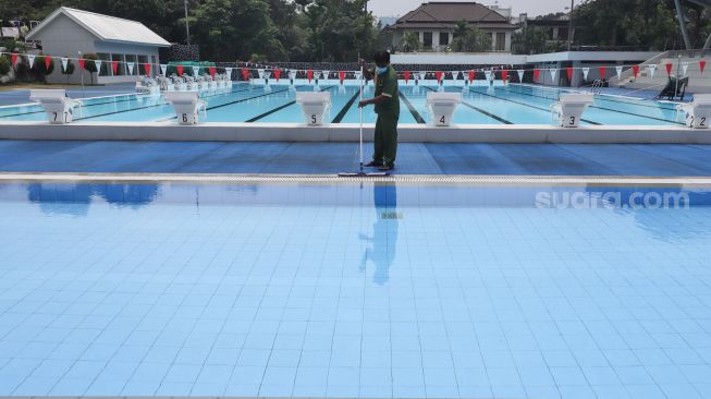 Petugas membersihkan dan merawat area kolam renang di Gelanggang Remaja Jakarta Selatan (GRJS) Bulungan, Kebayoran Baru, Jakarta Selatan, Rabu (6/4/2022). [Suara.com/Alfian Winanto]