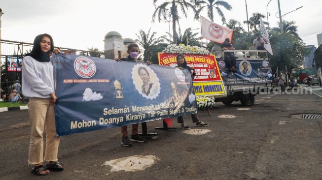 Massa memajang karangan bunga dengan foto Tn Paulin saat menggelar aksi demonstrasi di depan Gedung DPR RI, Jakarta Pusat, Rabu (6/4/2022). [Suara.com/Alfian Winanto]