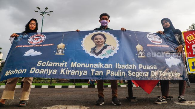 Massa memajang spanduk dengan foto Tan Paulin saat menggelar aksi demonstrasi di depan Gedung DPR RI, Jakarta Pusat, Rabu (6/4/2022). [Suara.com/Alfian Winanto]