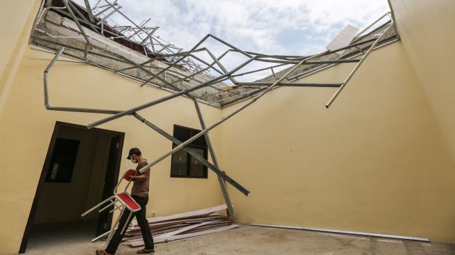 Pekerja merapihkan sisa puing atap yang ambruk di SDN Sawangan 1, Depok, Jawa Barat, Jumat (8/4/2022). [ANTARA FOTO/Asprilla Dwi Adha/foc]