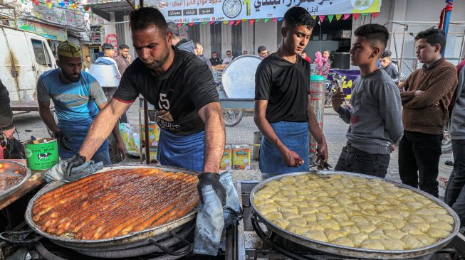 Pedagang memasak makanan berbuka puasa untuk dijual saat bulan Ramadhan di Gaza, Palestina, Minggu (3/4/2022). [MOHAMMED ABED / AFP]