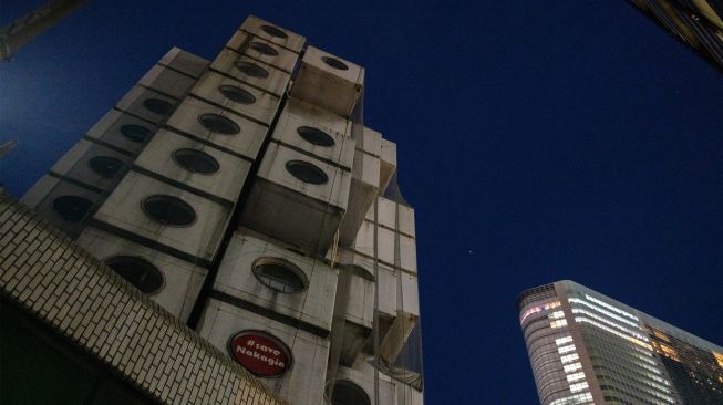 Menara Kapsul Nakagin yang terkenal (kiri) terlihat di distrik Ginza, Tokyo, Jepang, Rabu (6/4/2022). [Philip FONG / AFP]
