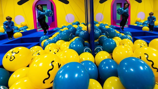 Anak-anak bermain dengan bola biru dan kuning di dalam Youseum di Solna, Stockholm, Swedia, Senin (4/4/2022). [Jonathan NACKSTRAND / AFP]