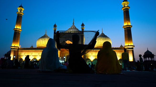  Seorang wanita Muslim menyesuaikan jilbabnya setelah berbuka puasa di Masjid Jama di kawasan Old Delhi, India, Kamis (7/4/2022). [Money SHARMA / AFP]
